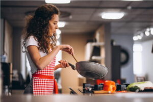 Девушка жарит еду на сковороде